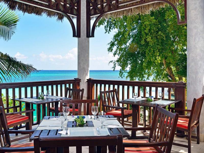 Venkovní terasa se stolkem, výhledem na moře a tropickou vegetaci.