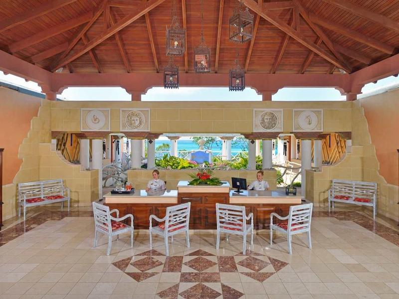 Otevřený bar v prostorném prostoru se dřevěným stropem a moderními bílými židlemi.