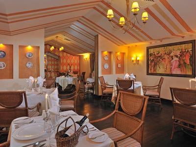 Elegantes Restaurantinterieur mit Holzmöbeln, weißen Tischdecken und warmer Beleuchtung.