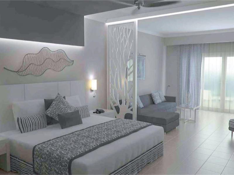 Moderní hotelový pokoj s velkou postelí, posezením a balkonem s výhledem na moře.