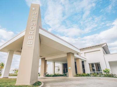 Modernes Hotel mit auffälligem Eingangsbereich und beige-farbenen Säulen unter blauem Himmel.