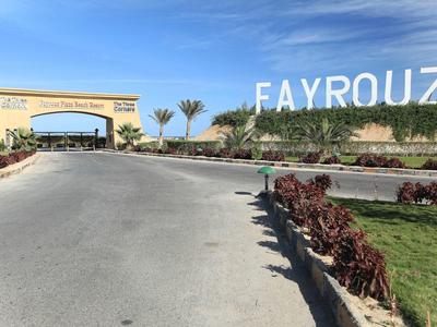Entrada ancha a un hotel con letras grandes 'FAYROUZ' en una colina bajo un cielo azul.
