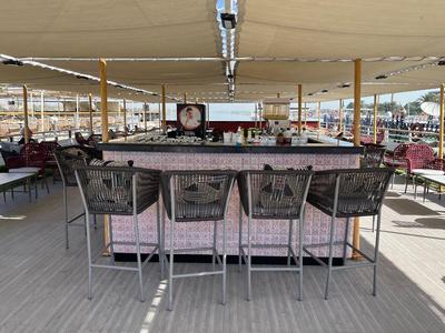 Otwarty bar z nowoczesnymi krzesłami i dużym daszkiem przeciwsłonecznym na zewnątrz hotelu