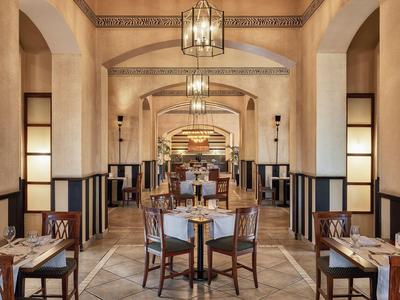 Elegancka, stylowa jadalnia z wysokimi łukami i ciepłym oświetleniem.