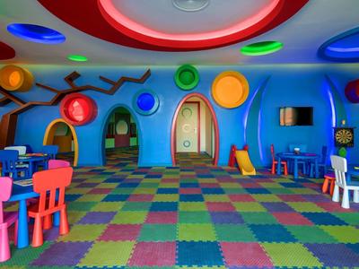 Salle de jeux colorée avec décoration ludique et chaises multicolores pour enfants.