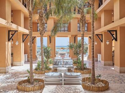 Innenhof eines Hotels mit Palmengarten, Springbrunnen und Blick auf das Meer.