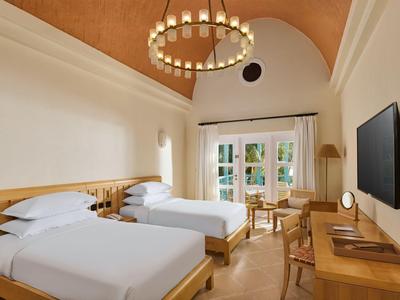 Helles Hotelzimmer mit zwei Einzelbetten, Holzmöbeln und großem Fensterblick.