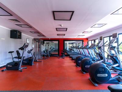 Geräumiger Fitnessraum mit vielfältigen Trainingsgeräten und großen Fensterfronten für viel Tageslicht.