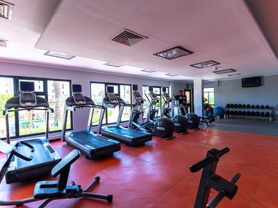 Heller Fitnessraum mit mehreren Laufbändern und Gewichten in einem Hotel.