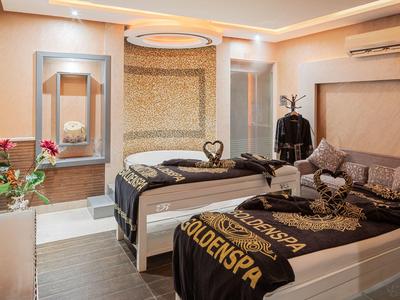 Gemütlicher Spa-Raum mit zwei Betten, warmem Licht und dekorativen Blumen und Handtüchern.