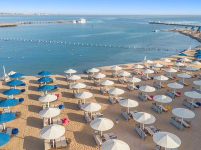 Strand mit Reihen von blauen und weißen Sonnenschirmen am ruhigen Meer.