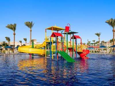 Bunter Wasserspielplatz mit Rutschen in einem Pool, umgeben von Palmen und Sonnenliegen.