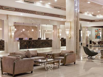 Elegante Lobby mit beigen Sitzen, Marmorsäulen, modernen Lampen und großem Empfangstresen.