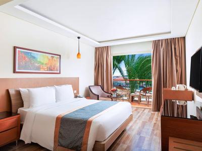 Helles Schlafzimmer mit Doppelbett, Holzfußboden, Balkon und Palmenblick, modern eingerichtet.
