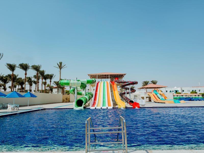 Wasserpark mit bunten Wasserrutschen und großem Pool unter klarem Himmel.