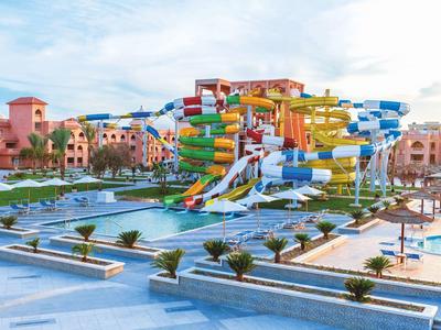 Großer bunter Wasserrutschenpark mit mehrere Pools und Palmen in sonnigem Resort.