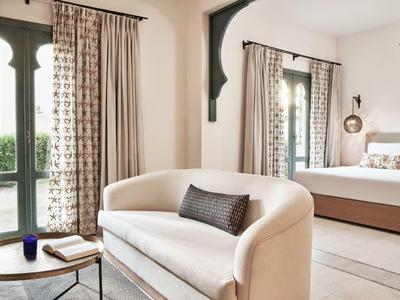 Helles Wohnzimmer mit cremefarbener Couch, schwarzem Kissen, rundem Holztisch und großem Spiegel.