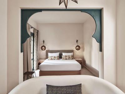 Camera d'hotel elegante con letto accogliente, cuscini morbidi e design raffinato.