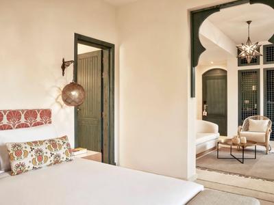 Helles Hotelzimmer mit gemütlichem Bett und Blick in einen elegant dekorierten Wohnbereich.