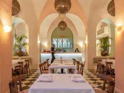 Elegantes Restaurant mit hohen Bögen, Holzmöbeln und warmem Licht.