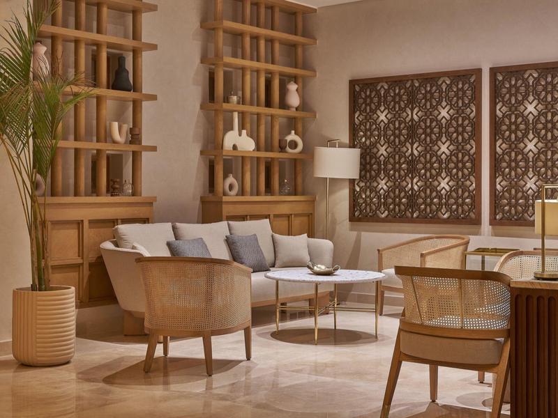 Modern eingerichtetes Wohnzimmer mit Holzregalen, beigen Sesseln und dekorativen Wandpaneelen.