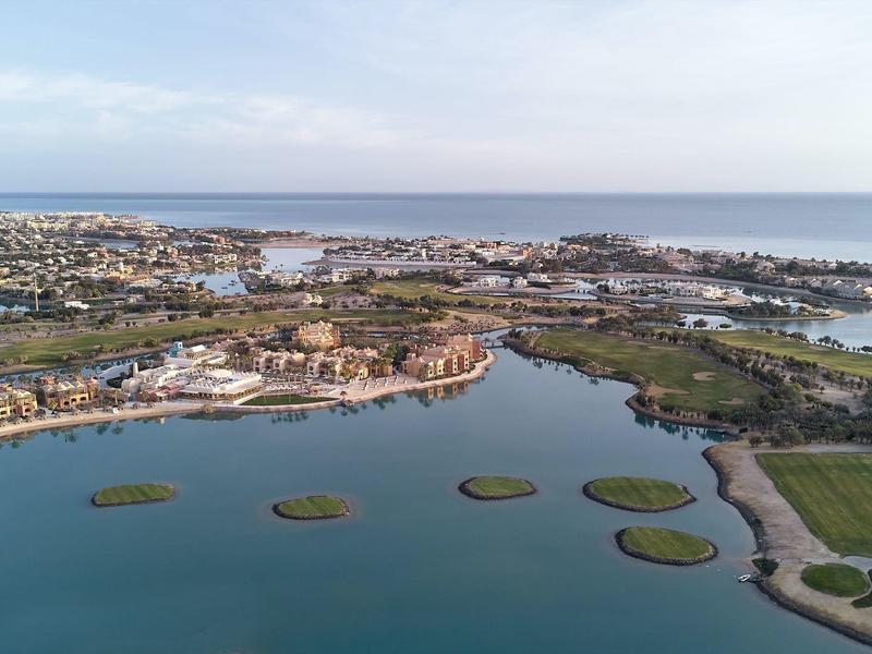 Luftaufnahme einer Küstenstadt mit grünem Land, Wasserflächen und Inseln im ruhigen Meer.