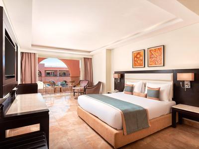 Modern eingerichtetes Hotelzimmer mit großem Bett und Balkon mit Meerblick.