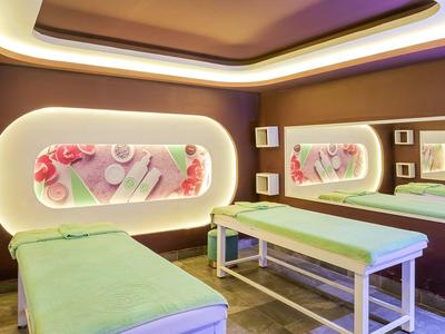 Moderne Massagepraxis mit grünen Liegen, indirekter Beleuchtung und dekorativen Wandbildern.