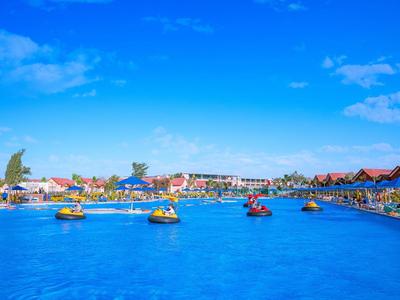 Menschen fahren Wassermotorräder auf klarem blauem Wasser mit Gebäuden im Hintergrund.