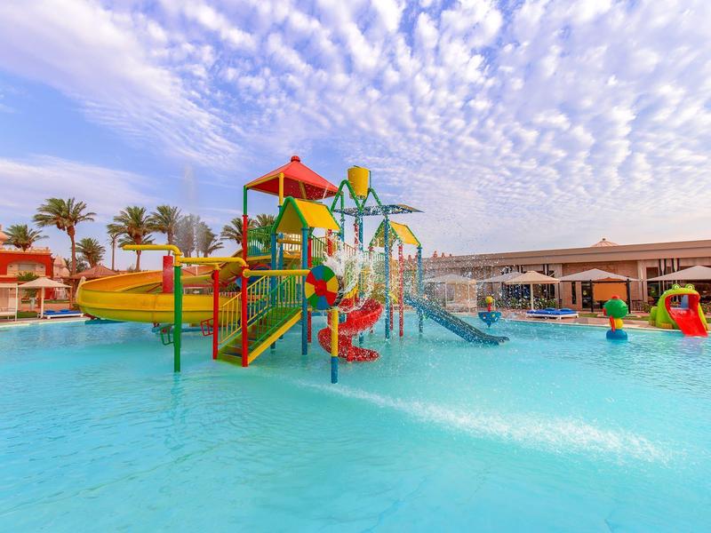 Buntes Wasserspielgerät mit Rutschen und Spritzfiguren im flachen Pool unter blauem Himmel.
