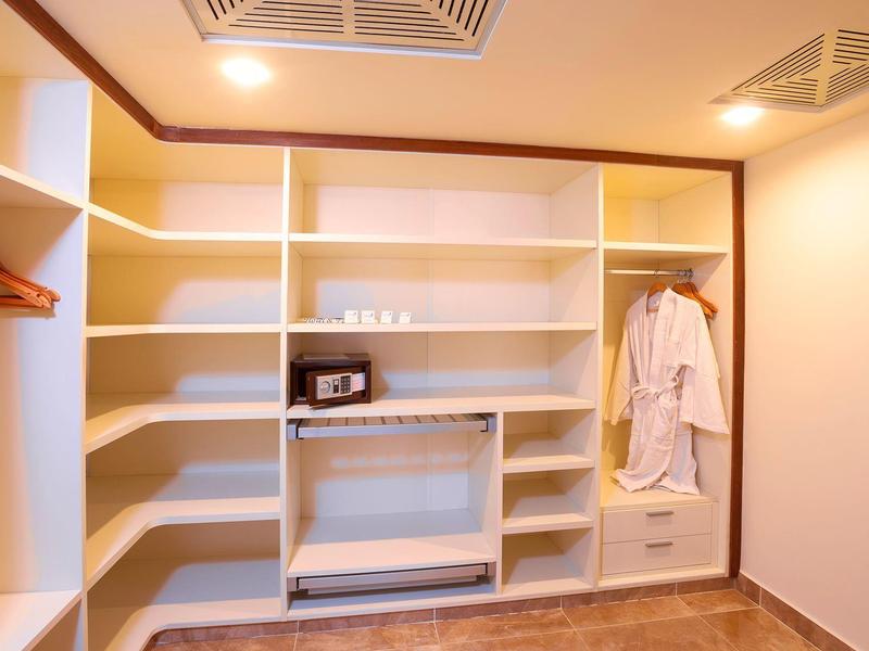 Heller begehbarer Kleiderschrank mit weißen Regalen, Holzboden und zwei weißen Bademänteln.