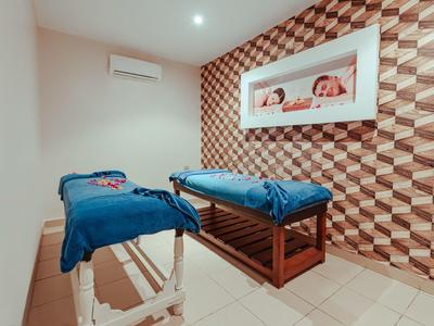 Ein gepflegter Massageraummit zwei Liegen, einer gemusterten Wand und kühler Beleuchtung.