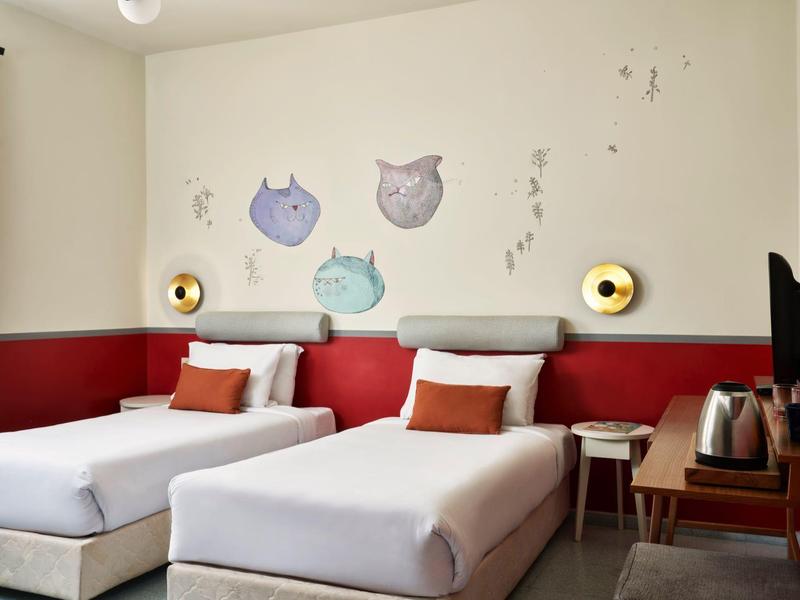 Modernes Schlafzimmer mit zwei Einzelbetten, roten Wandakzenten und Eulen-Wandtattoos.