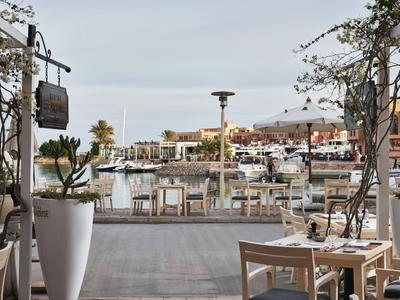 View from a restaurant with tables overlooking a marina under cloudy sky.
