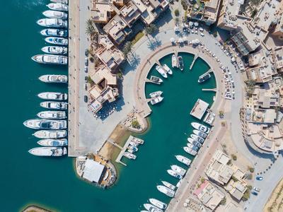 Aerial view of a marina with multiple boats and surrounding buildings by the water.