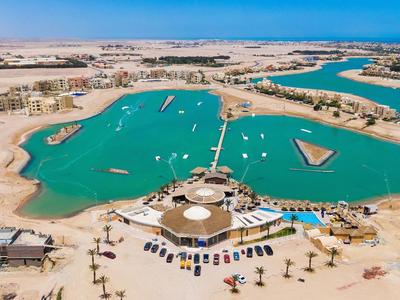 Aerial view of an artificial lagoon with sandy beach and surrounding buildings in a desert landscape.