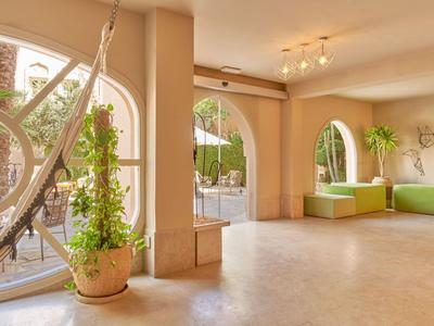 Bright lounge with large arches, plants, and hammocks in a hotel area.