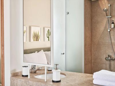 Modern hotel shower with glass partition, white towels, and mirror surface.