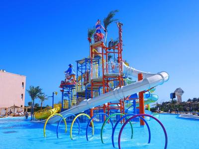 Kleurrijke waterspeeltuin met glijbanen en waterattracties in een hotelzwembad bij heldere blauwe lucht.