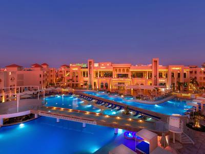 Hotel moderno con area piscina illuminata al crepuscolo.