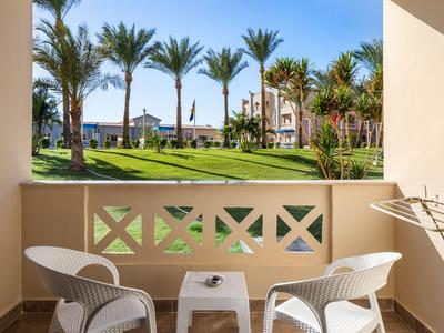 Balcone con sedie bianche e tavolo che si affaccia su palme tropicali e edifici dell'hotel.