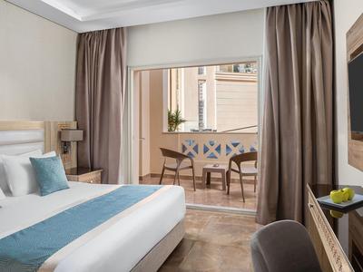 Camera d'hotel moderna con terrazza, letto con accenti blu e zona pranzo all'aperto.