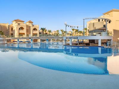 Grande piscina dell'hotel con bar e più edifici sotto un cielo sereno
