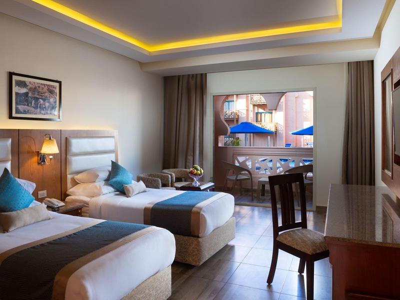 Modernes Hotelzimmer mit zwei Einzelbetten, Holzmöbeln und Balkon mit Meerblick.