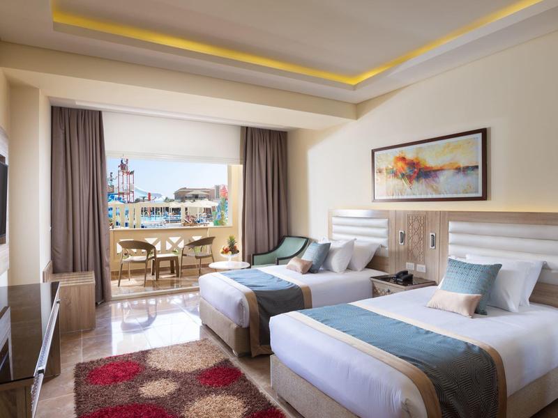 Modernes Hotelzimmer mit zwei Einzelbetten, großem Fenster und Balkon mit Meerblick.