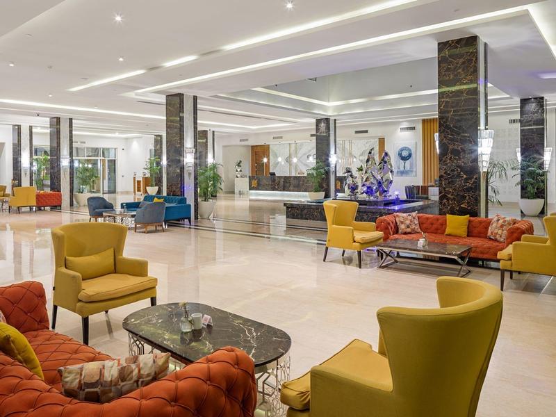 Großer moderner Hotellobby mit bunten Sesseln und Sofas sowie einer Empfangstheke im Hintergrund.