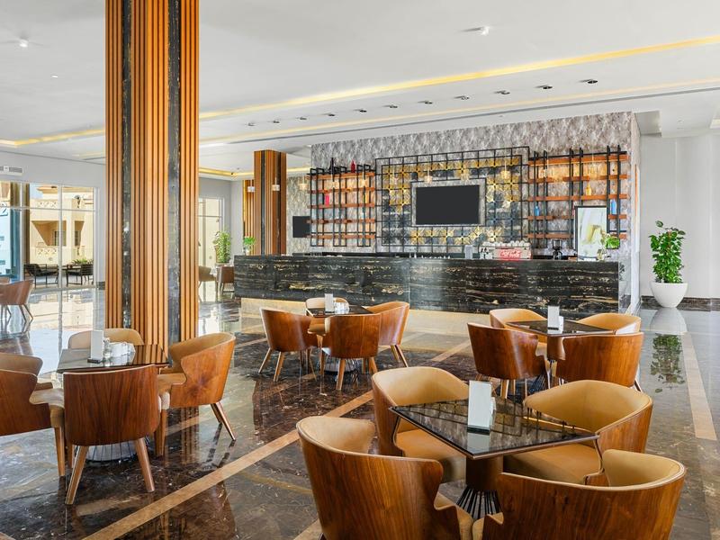 Moderne Bar mit runden Holztischen, braunen Lederstühlen, schwarzer Theke und hellem Marmorboden.