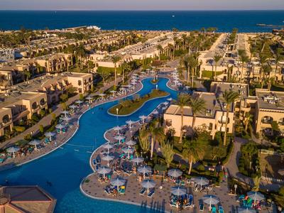 Luxury hotel resort with large pools, sun umbrellas, and direct sea view on a clear day.