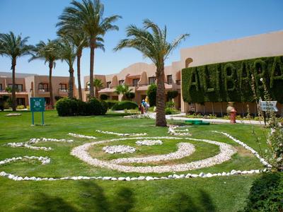 Hotel garden with palm trees, lawn, and decorative stones under a blue sky