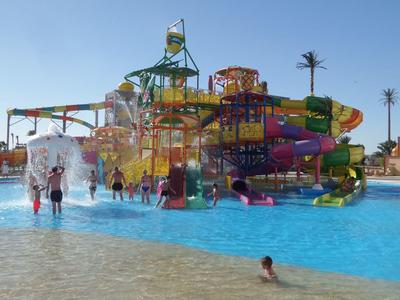 Water park with colorful slides and people in pool under clear sky